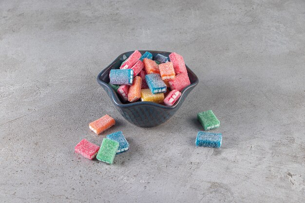Colorful licorice in round black bowl placed on marble background.