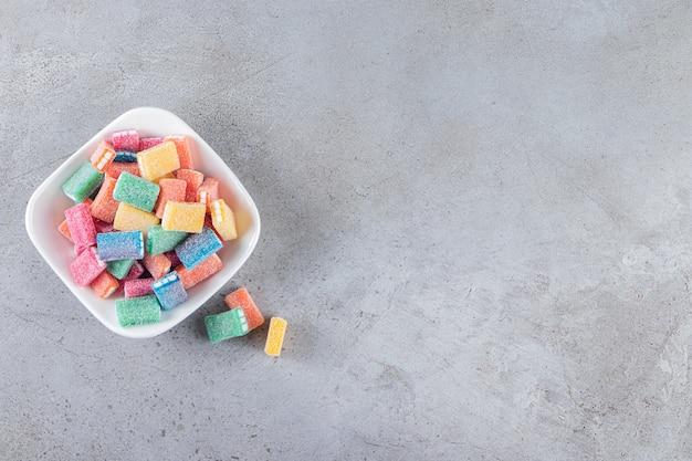 Colorful licorice in white deep bowl placed on stone table.