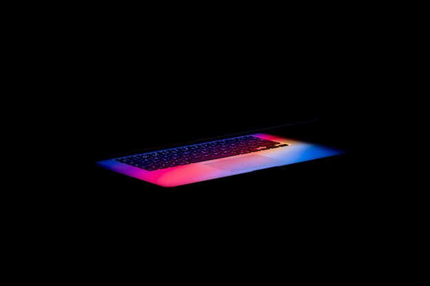 暗闇の中でノートパソコンの画面から出てくるカラフルな光