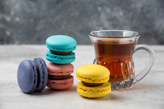 Foto gratuita macarons colorati con una tazza di tè nero sul tavolo bianco.