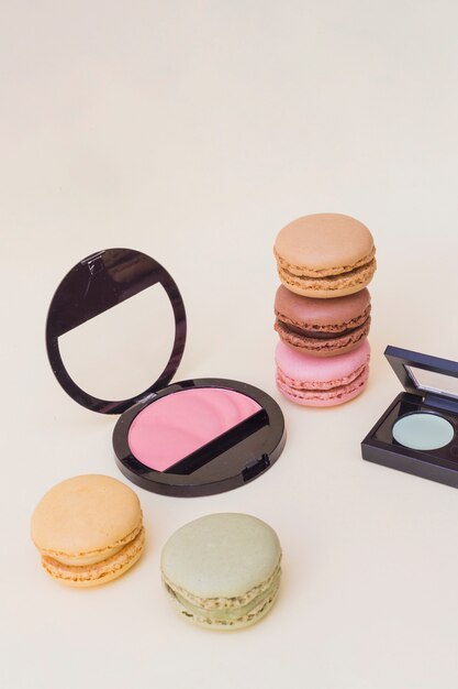 Colorful macaroons with pink blusher on beige background