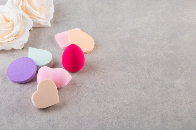 Colorful make-up sponges placed on a stone table.