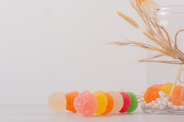 Colorful marmalades and glass jar on white.