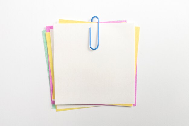 Цветастый штырь бумаги примечания с голубыми бумажными зажимами и изолированный на белизне.