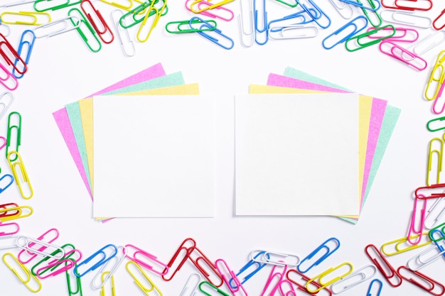 Colorful paper clips and note papers in the centre of composition isolated on white.