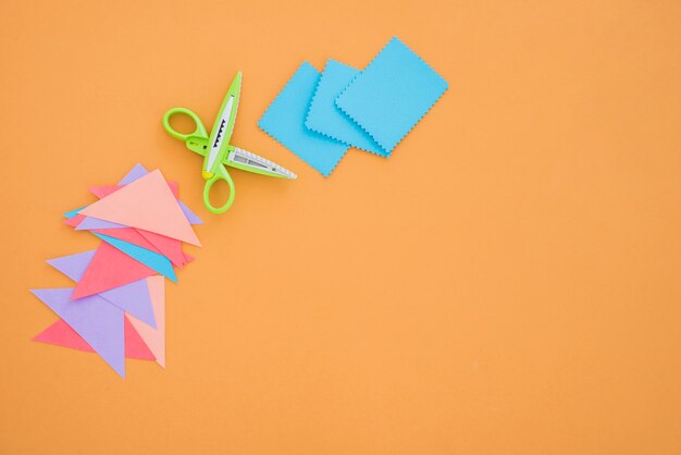 Colorful paper and scissor on colored backdrop