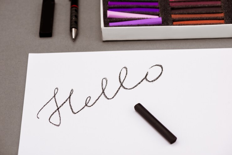Free Photo colorful pastel, pen, paper with word hello on grey table