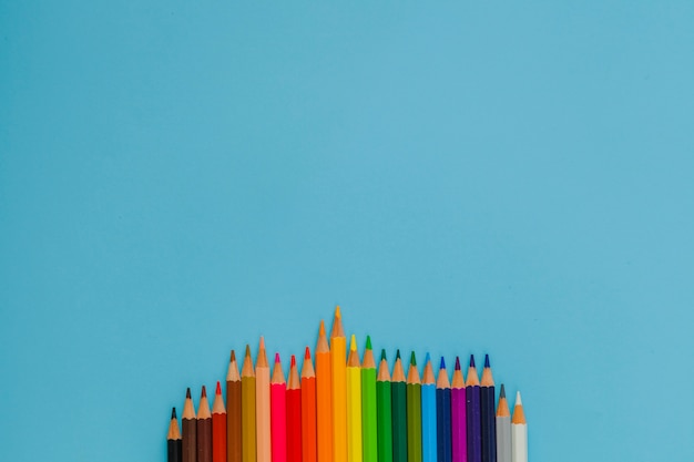 Colorful pencils arranged on blue