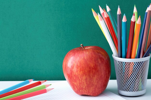 Colorful pencils with apple on a notepad