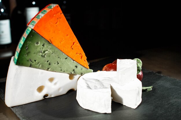 Colorful pieces of cheese lie on black dish