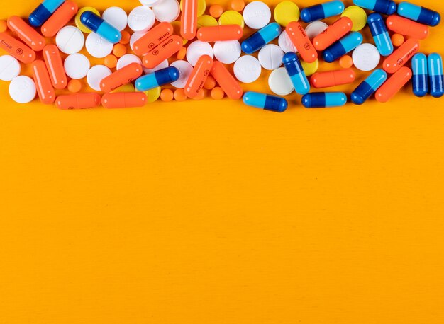 Colorful pills on a orange surface