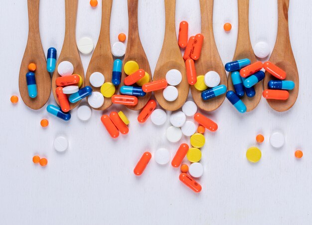 Colorful pills in wooden spoons