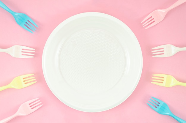 Colorful plastic dishes on pink background