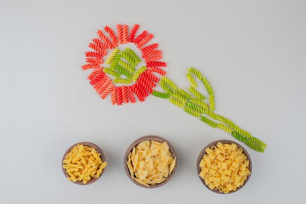 Colorful raw macaroni as a flower on white