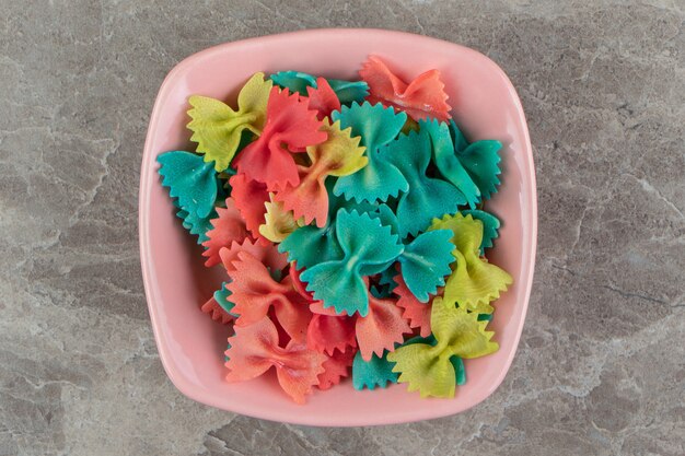 Colorful ribbon pasta in pink bowl.