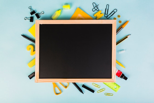 Free photo colorful school and office supplies around chalkboard