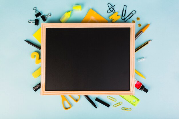 Colorful school and office supplies around chalkboard 