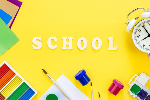 Free photo colorful school supplies and wooden letters on a yellow background back to school concept top view