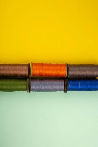 Colorful sewing threads on a yellow-green desk