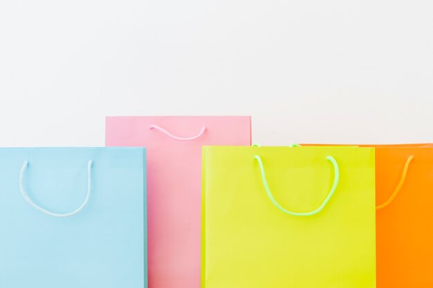 Colorful shopping bags on white surface