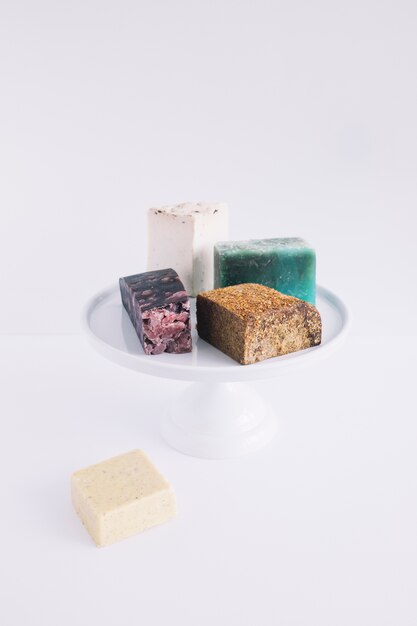 Colorful soap bars on cake stand over white background