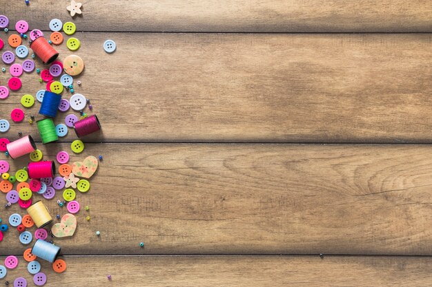 Colorful spools and buttons on wooden backdrop