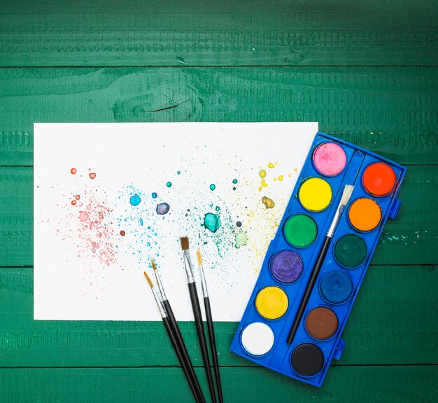 colorful stains abstract painting on white paper with paintbrush and watercolor palette