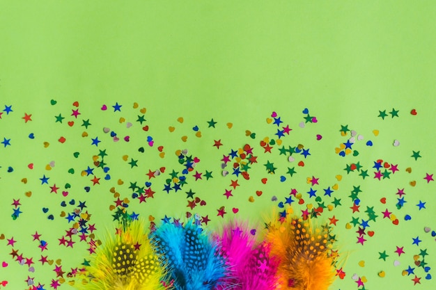 Colorful sticks with confetti underneath on a green table