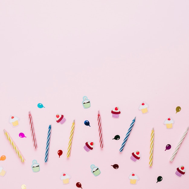 Colorful striped candles with birthday stickers on pink background