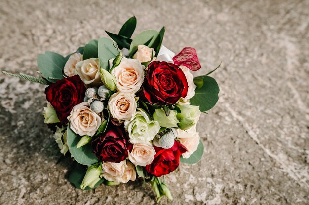赤い花のバラとユーカリの緑と花嫁の手の結婚式の花束 プレミアム写真
