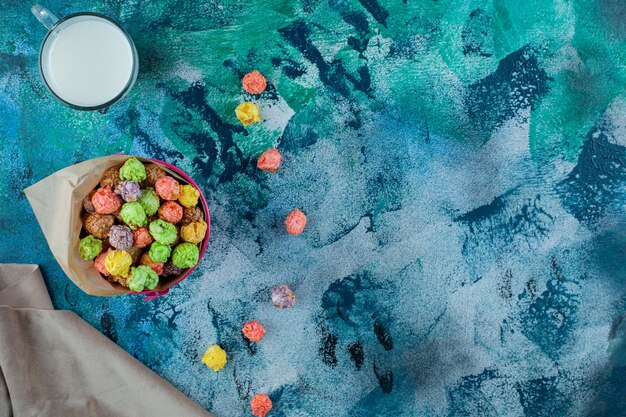 Colorful sugar cereal in a bucket on the blue surface