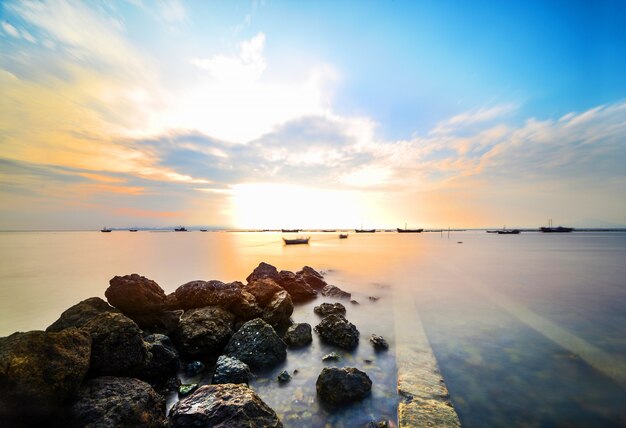 海で岩とカラフルな夕日