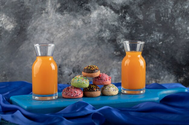 ジュースのガラス瓶とお茶のカップとカラフルな甘いドーナツ。