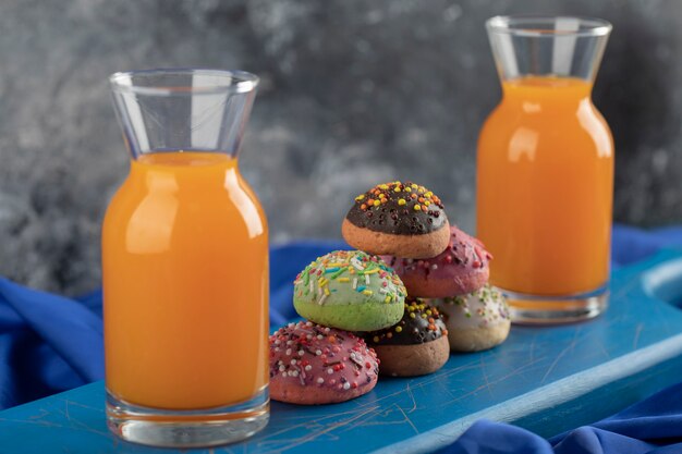 Colorful sweet doughnuts with glass jars of juice and a cup of tea. 