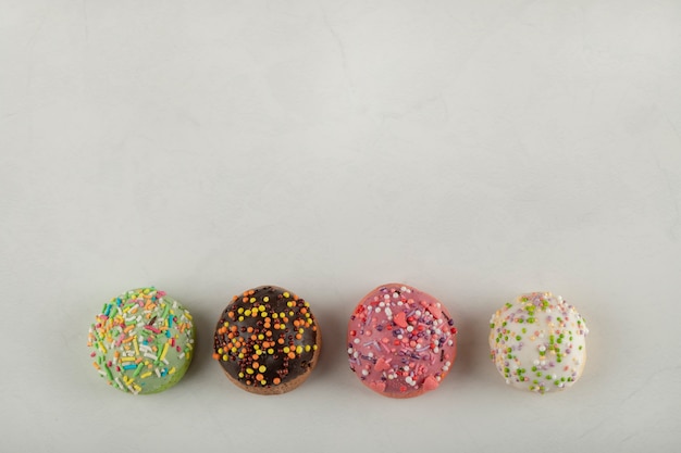 Colorful sweet small doughnuts on a white surface.