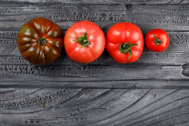 Colorful tomatoes top view on a grey wooden wall