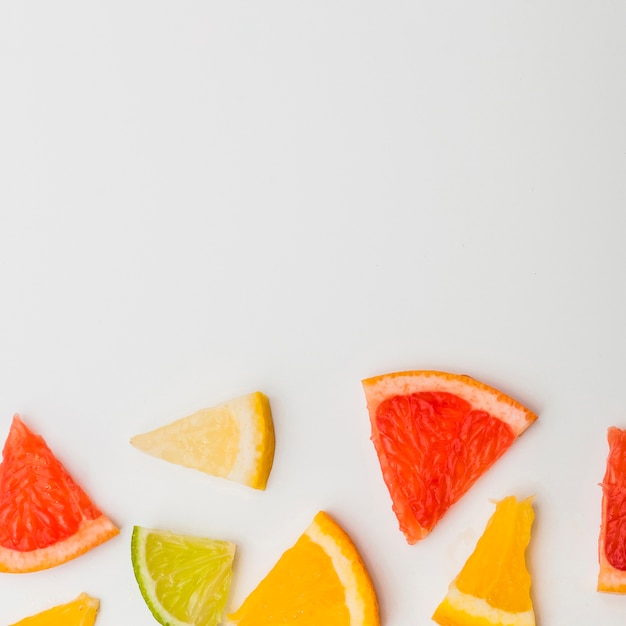 Fetta triangolare colorato di pompelmi; limone e un'arancia su sfondo bianco