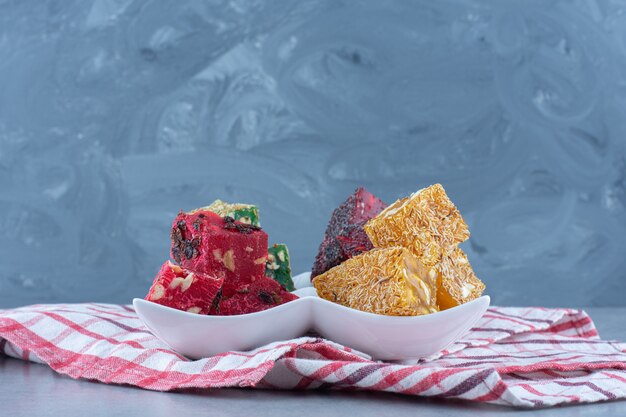 Colorful Turkish delight flavors on a bowl, on the tea towel, on marble table. 