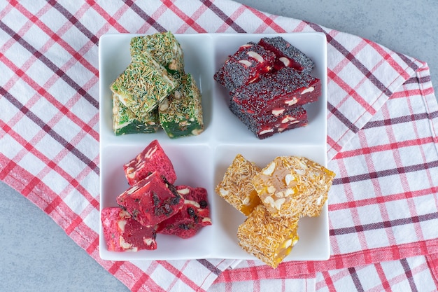 Colorful Turkish delight flavors on a bowl, on the tea towel, on marble table. 