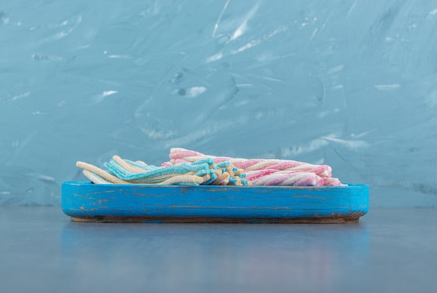 Free photo colorful twisted candies on blue plate.