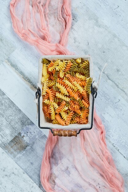 Colorful uncooked pasta with pink tablecloth.