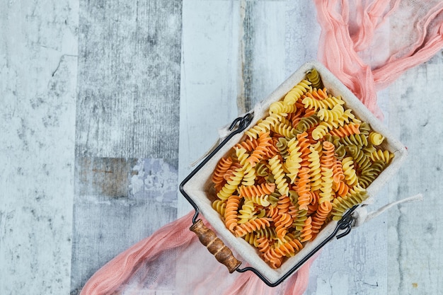 Free photo colorful uncooked pasta with pink tablecloth.