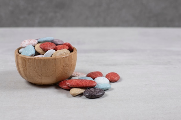 Colorful various stone candies in wooden bowl.