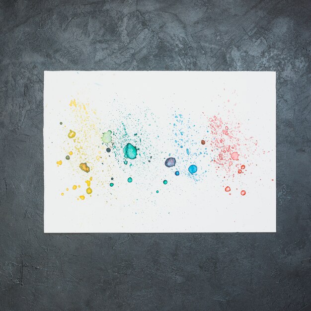 Colorful water color stain on white paper over black backdrop