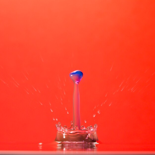 Colorful waterdrop falling on red
