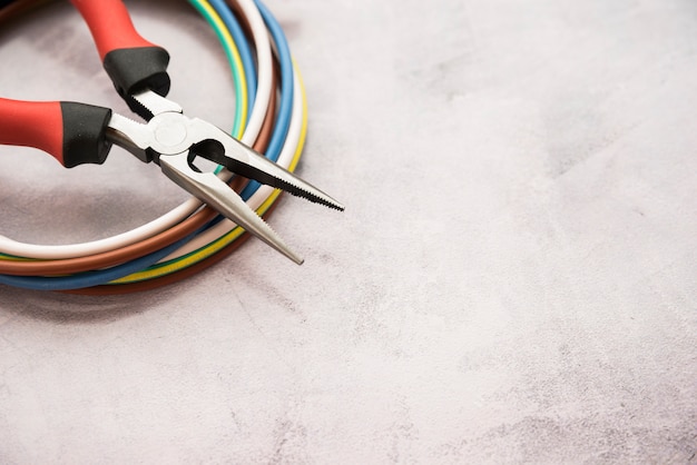 Colorful wire and plier on gray concrete background