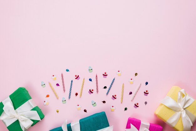 Colorful wrapped gift boxes; candles and birthday stickers on pink background