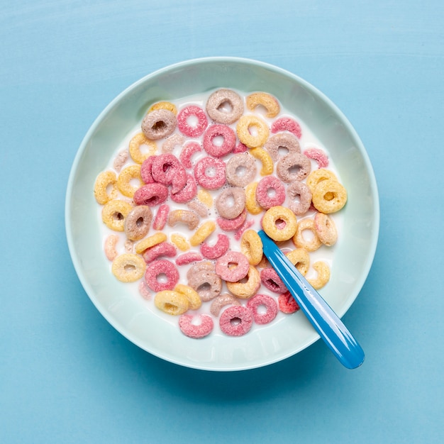 Foto gratuita cereale variopinto in ciotola e cucchiaio blu