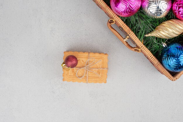 Colourful Christmas balls in basket with cookies in rope . 