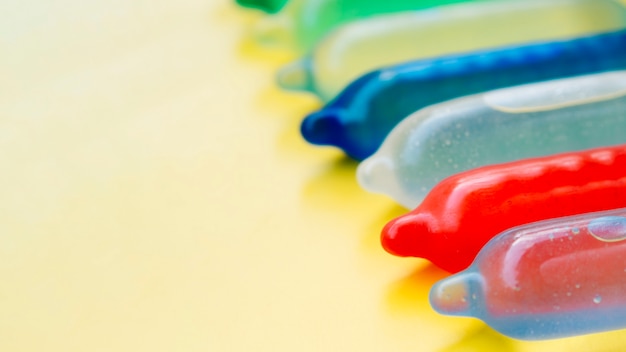 Free photo colourful condoms filled with water on yellow background